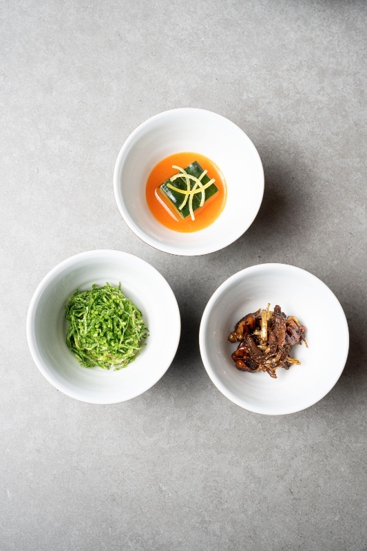 Banchan by Soigne which include cucumber and paprika, clam and Doenjang along with Pecan paired with anchovy.